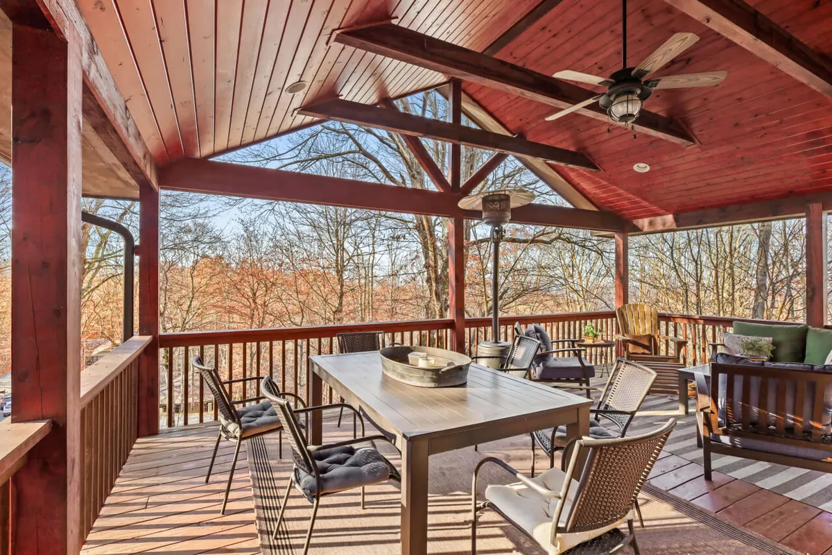A well-appointed outdoor dining area on the deck, featuring a comfortable table set and seating, all with a backdrop of lush trees. The setup is perfect for alfresco meals and socializing in the mountain air.