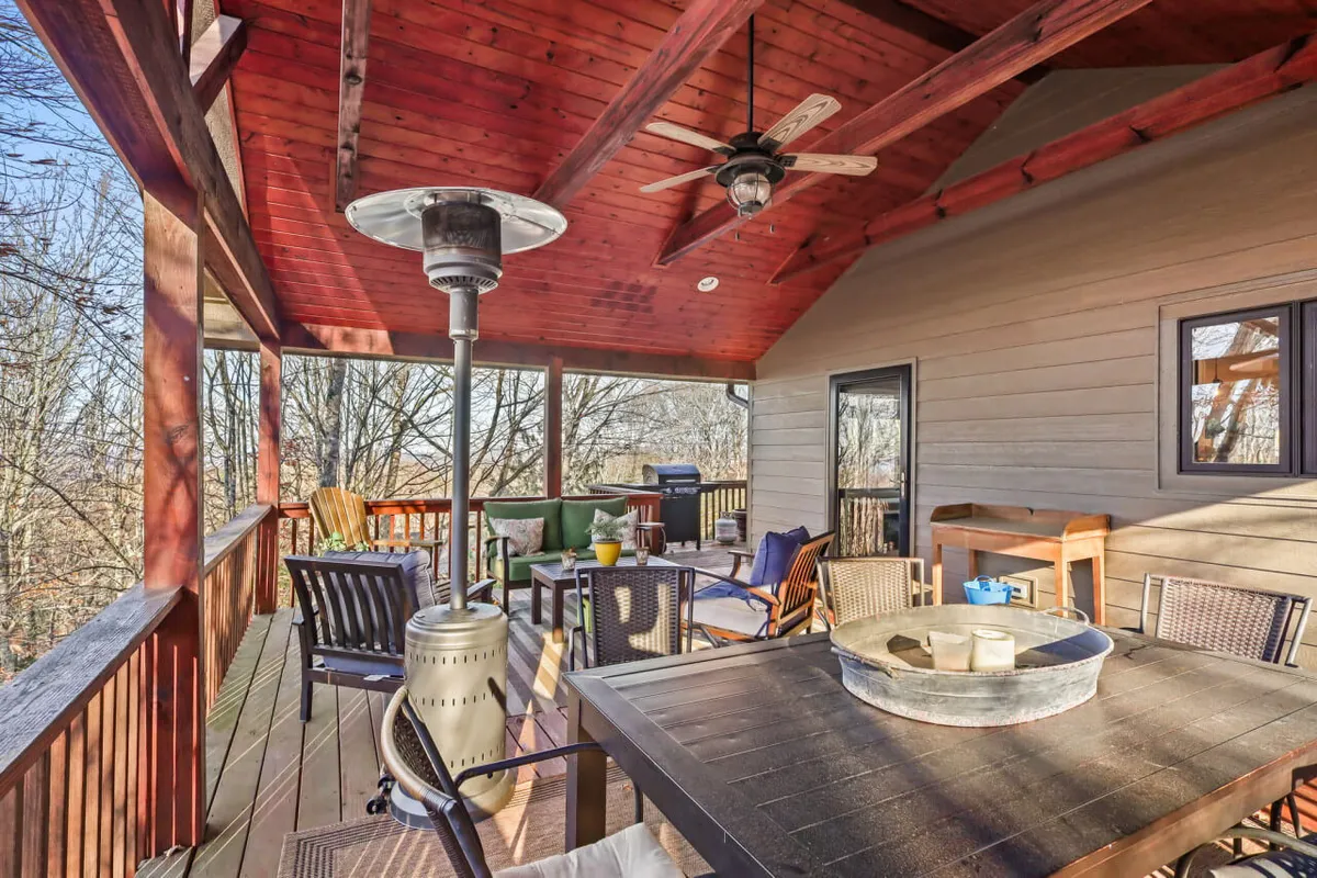 An outdoor seating area with a decorative table, comfortable chairs, a heating lamp, and a wooden ceiling. The setting is designed for cozy evenings and intimate gatherings, with views of the sunset and the surrounding landscape.