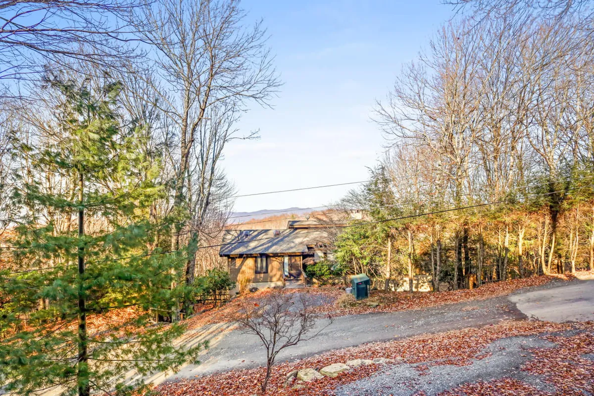 A wide view of the property’s exterior, including the house, surrounding trees, and a winding driveway. The tranquil scene hints at nature walks, wildlife observation, and easy access to nearby outdoor adventures, reinforcing the cabin’s prime location in the High Country.