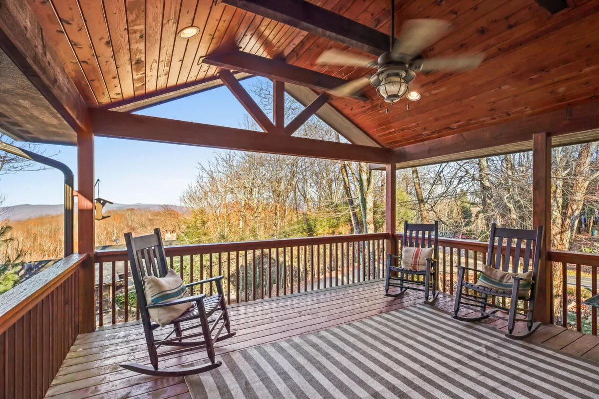 A peaceful exterior deck featuring classic rocking chairs and a wooden ceiling, opening up to mountain views. The setting is tranquil, inviting guests to unwind, read, or simply take in the beauty of Beech Mountain's sunsets and natural surroundings.