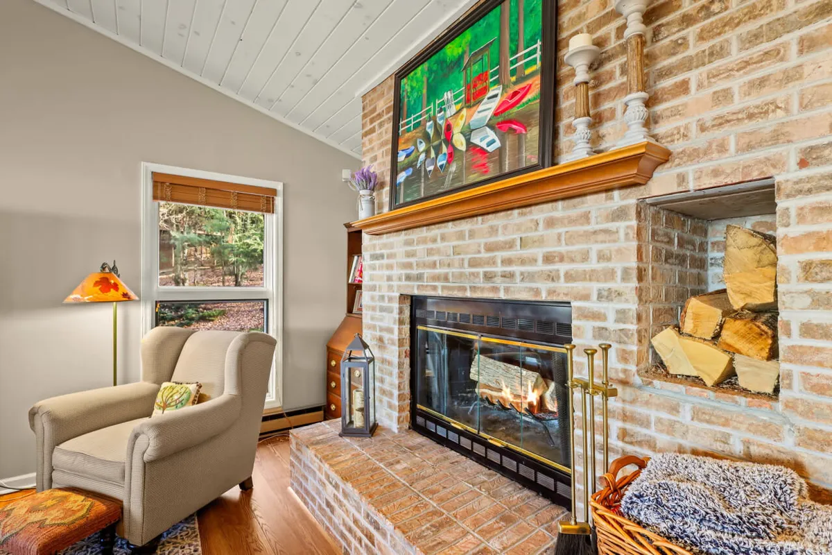 A living area with a striking fireplace, armchair, window, and colorful painting, creating a relaxed and artistic vibe. The space is perfect for reading or enjoying a warm drink, especially during the colder months.
